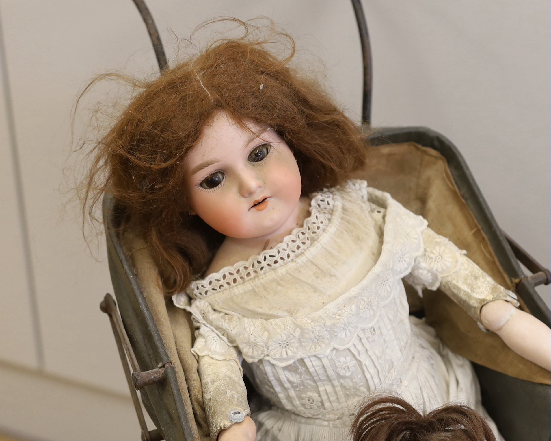 An Armand Marseille open mouth doll, a Heubach Koppelsdorf open mouth doll and an upright dolls pram, pram 66cm high